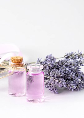 Kokulu lavanta yağı, kurutulmuş lavanta buketi ve beyaz havlular.