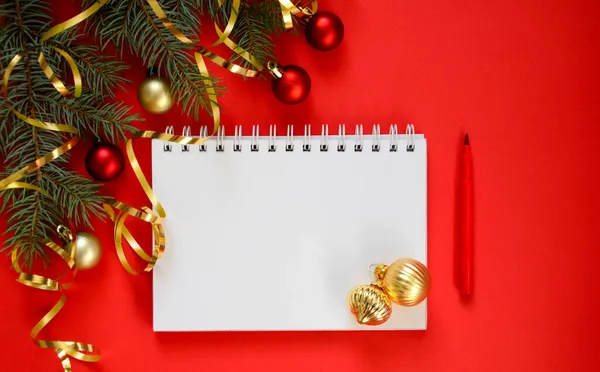 Yeni yıl hedef listesi 2022. Yılbaşı ağacı, kırmızı parıltılı top ve altın kurdeleli kırmızı zemin üzerine kurulmuş yeni yıl hedeflerinin ve kararlarının listelenmesi hakkında yazmak için temiz bir defter. Dilek listesi.