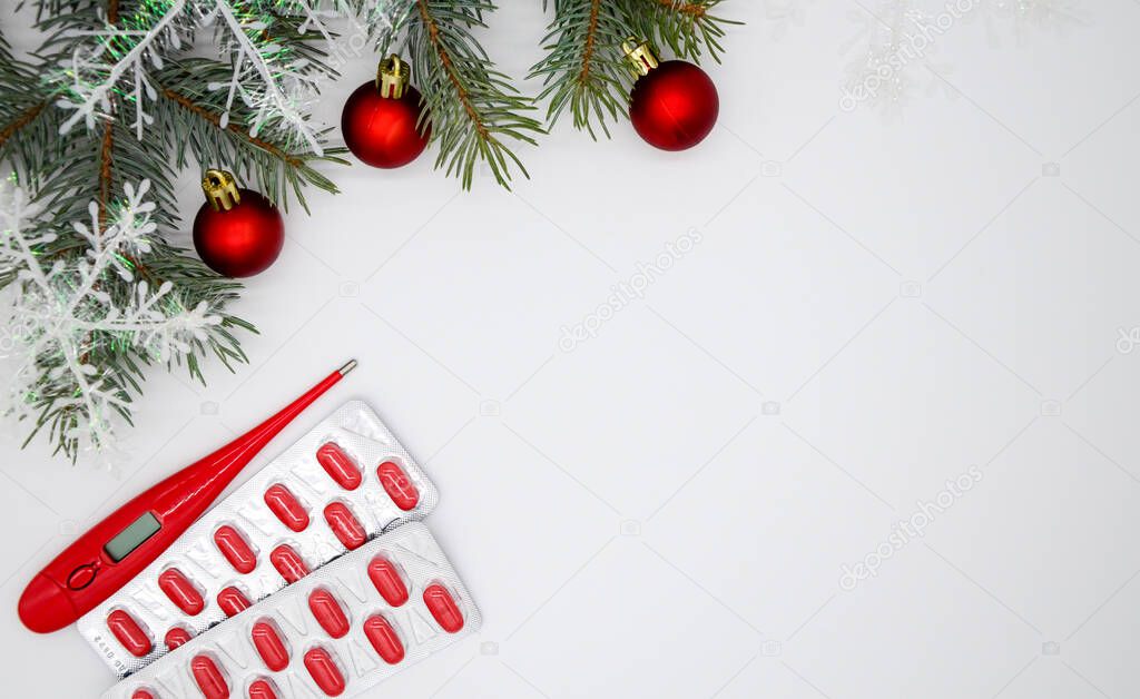 Blisters with red capsules, pills and Christmas tree with snowflakes and three new year's red balls, a red thermometer on a white background with copy space. Christmas medical flatly.