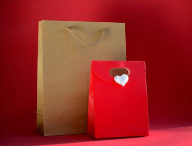 Hediye çantası ve kırmızı arka planda fotokopi alanı olan kırmızı kağıt çanta. Sevgililer Günü hediyesi, 8 Mart, Anneler Günü, doğum günü.