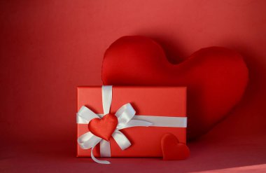 Kırmızı hediye kutusu, beyaz yay ve kırmızı arka planda kalpler. Sevgililer Günü hediyesi, 8 Mart, Anneler Günü, doğum günü.
