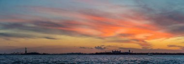 Hudson Nehri üzerinde gün batımı, Ellies Adası ve arka planda Özgürlük Heykeli, New York, ABD