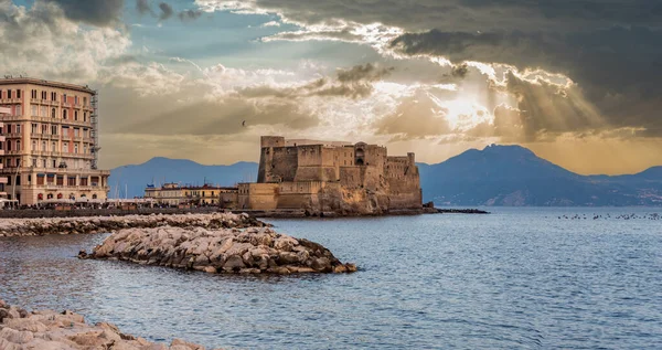 Napoli Körfezi, Güney İtalya 'daki ikonik Castel Dell' Ovo 'da yağmurdan sonra manzaralı güneş ışınları