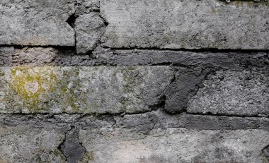 Yüzeyinde yosun büyüyen eski beton tuğla duvar ve tuğla dokusu arkaplanı arasında görünür harç