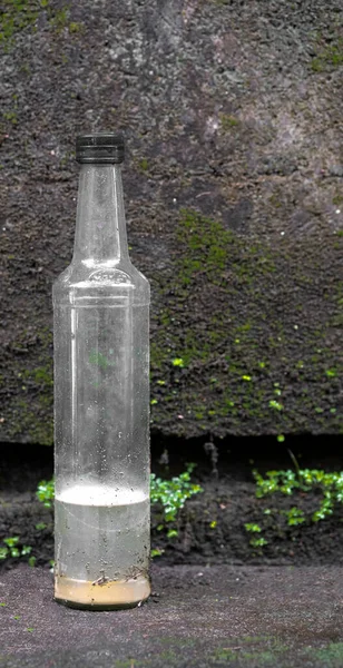 Dirty Bottle Nose Glass Bottle Label Liquid Standing Concrete Ground — Foto Stock