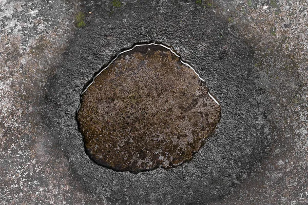 Round water puddle on concrete pavement in Bali, Indonesia