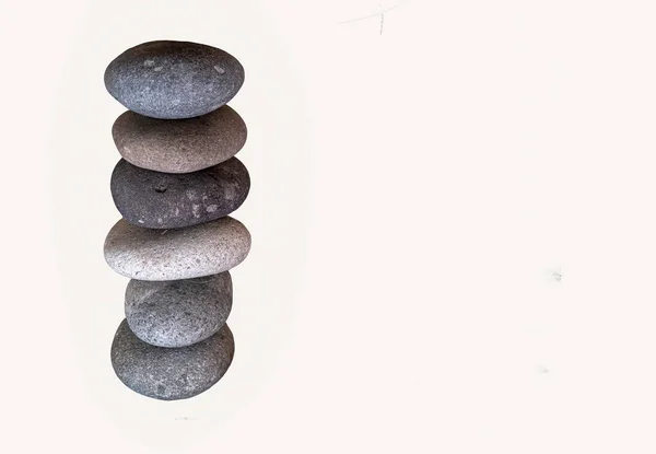 Multi color river stones stacked vertically against white background. Copy space