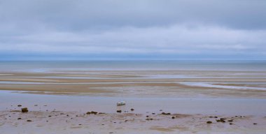 Dalgalar alçaldığında yüzen yelkenli teknesiyle Cape Cod sahili manzarası.