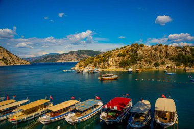 Marmaris, MUGLA, TURKEY: Türkiye 'nin Marmaris kenti yakınlarındaki Mugla' da güneşli bir yaz günü, Turunch sahilindeki kayıklar ve dağlar plajın en üst görüntüsü.