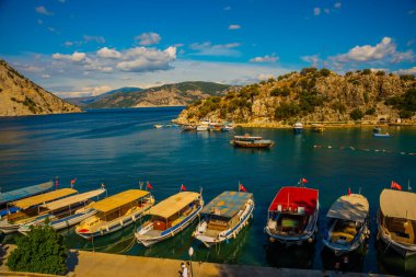 Marmaris, MUGLA, TURKEY: Türkiye 'nin Marmaris kenti yakınlarındaki Mugla' da güneşli bir yaz günü, Turunch sahilindeki kayıklar ve dağlar plajın en üst görüntüsü.