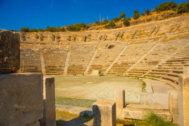 Güneşli bir günde antik amfiteatr manzaralı bir peyzaj. İkinci yüzyılda inşa edilen bu eser, klasik Yunan tiyatrosuna iyi bir örnek teşkil ediyor..