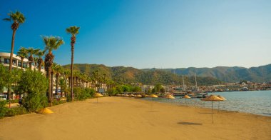 Türkiye 'nin Marmaris kentindeki kumsalda güneşli bir günde Akdeniz ve dağların manzarası.