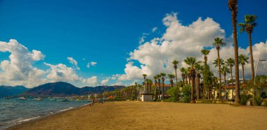 Türkiye 'nin Marmaris kentindeki kumsalda güneşli bir günde Akdeniz ve dağların manzarası.