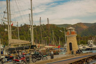 Marmaris, MUGLA, TURKEY: bulutlu bir günde gemi ve yatların rıhtımında deniz feneri manzarası.