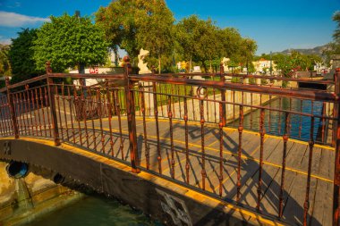 MARMARIS, MUGLA, TURKEY: Şehir manzarası kanal ve çeşme ile güneşli bir günde balık heykelleri ile modern ticaret merkezi arka planda