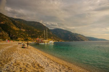 OLUDENIZ, FETHIYE, TURKEY: Oludeniz sahilindeki iskelede turistli korsan dekoratif gemi. Oludeniz sahili ve bulutlu deniz manzaralı güzel bir manzara..
