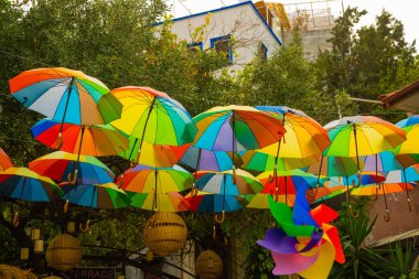 Arka plan renkli şemsiyeler. Gökyüzünde, caddenin üzerinde palmiye ağaçlarına karşı yüzen çok renkli şemsiyeler. Şemsiye sokak dekorasyonu.