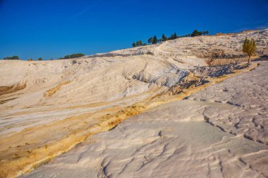 PAMUKALE, DENIZLI, TURKEY: Güneşli bir günde güzel beyaz travertin terasları. Türkiye 'nin en ünlü eğlencelerinden biri olan Pamukkale, bir Unesco Dünya Mirası sahası..
