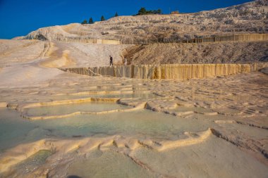 PAMUKALE, DENIZLI, TURKEY: Güneşli bir günde güzel beyaz travertin terasları. Türkiye 'nin en ünlü eğlencelerinden biri olan Pamukkale, bir Unesco Dünya Mirası sahası..