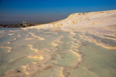 PAMUKALE, DENIZLI, TURKEY: Güneşli bir günde güzel beyaz travertin terasları. Türkiye 'nin en ünlü eğlencelerinden biri olan Pamukkale, bir Unesco Dünya Mirası sahası..