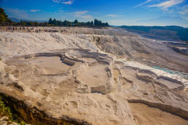 PAMUKALE, DENIZLI, TURKEY: Güneşli bir günde güzel beyaz travertin terasları. Türkiye 'nin en ünlü eğlencelerinden biri olan Pamukkale, bir Unesco Dünya Mirası sahası..