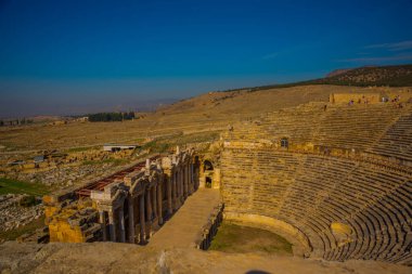 PAMUKALE, DENIZLI, TURKEY: Pamukkale 'de güneşli bir günde mavi bir gökyüzünün arka planında antik amfitiyatro. Hierapolis harabe şehri..