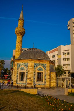 Güneşli bir günde Konak Camii olarak da anılan Yali Camii. Konak Meydanı 'nda, Valilik Konağı' nın ve Saat Kulesi 'nin yanında yer alır..