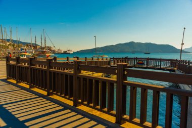Marmaris, MUGLA, TURKEY: Güneşli bir günde Marmaris 'te deniz kenarındaki gezinti güvertesinde kanal ve ahşap köprü.