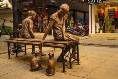 MARMARIS, MUGLA, TURKEY: A modern monument of a girl and a boy on a bench on the street in Marmaris.