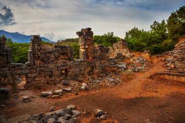 PHASELIS, KEMER, TURKEY: Ruins of the amphitheatre of the ancient city of Phaselis on mountains and clouds background in Turkey, Antalya province, near Kemer.