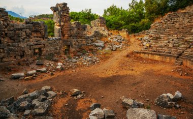 PHASELIS, KEMER, TURKEY: Ruins of the amphitheatre of the ancient city of Phaselis on mountains and clouds background in Turkey, Antalya province, near Kemer.
