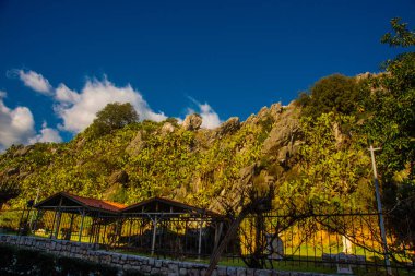 Iuilik Arkeoloji Parkı ya da Refah Kayaları, güneşli bir günde mavi bir arka planda, Marmaris 'in merkezindeki bir yamaçta bulunan eşsiz bir açık hava müzesidir..