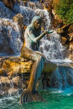 Marmaris 'in göbeğindeki yapay bir şelaledeki deniz kızı anıtı güneşli bir günde turkuaz suyla.