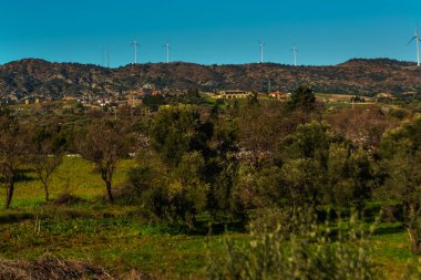 KNIDOS, DATCA, MUGLA, TURKEY: Güneşli bir günde tatil beldesi Datca 'daki Tarlalar, dağlar ve yel değirmenleri manzaralı güzel manzara.
