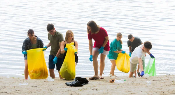a team of teenagers collect garbage on the river bank