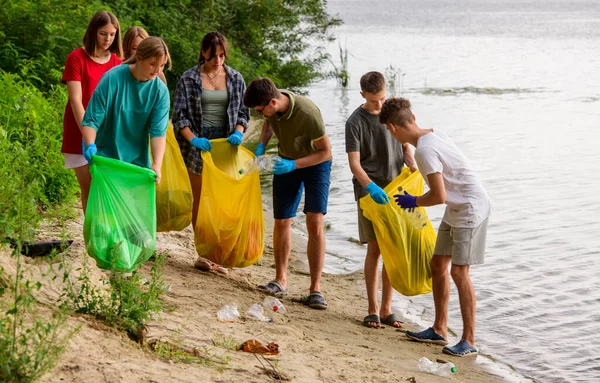 a team of teenagers collect garbage on the river bank