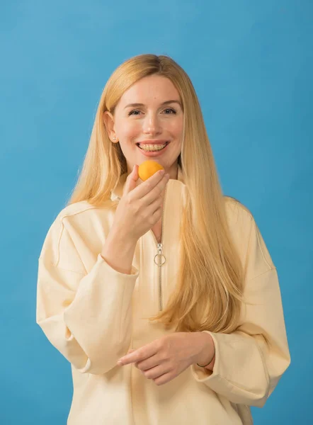 Elinde kayısı ve diş teli olan gülümseyen bir kızın portresi.