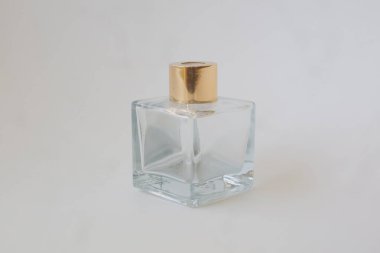 Beyaz izole arka planda altın kapaklı cam parfüm şişesi