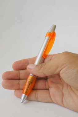 Elinde turuncu bir kalem resmi var.