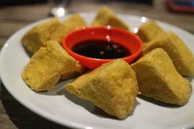 Kızarmış tofu ve soya sosu beyaz tabakta.