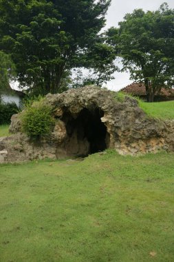 Parkın ortasında yeşil çimen fotoğraflı yapay bir mağara.