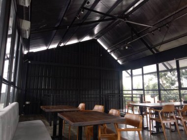 Siyah duvarları, tahta sandalyeleri ve masa fotoğrafı olan boş bir oda.