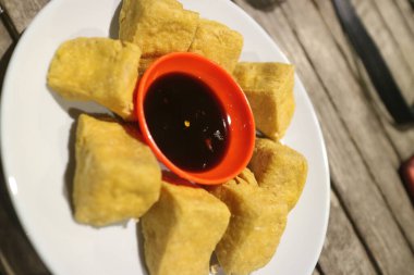 Kızarmış tofu ve soya sosu beyaz tabakta.