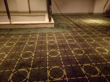 Odada yuvarlak ve kare motifli koyu kahverengi bir halının fotoğrafı.