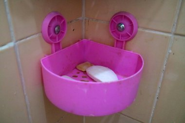 Banyonun duvarına yapışmış mor bir sabun tutacağının fotoğrafı.