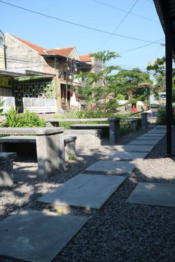 Bir masa ve yol kenarındaki çimentodan yapılmış sandalyelerin fotoğrafı.