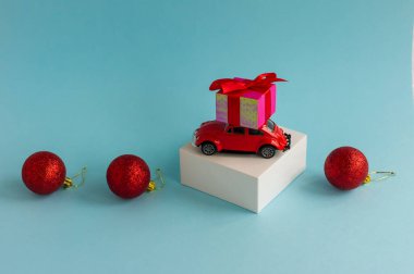Çatıda hediye kutusu olan kırmızı oyuncak araba ve mavi arka planda kırmızı takılar. Metnin için bir kopya alanı