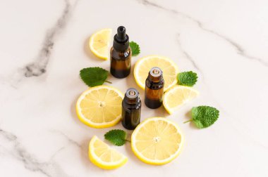Kozmetik şişelerinde limon yağları ve mermer bir masa üzerinde limon merhemi var.