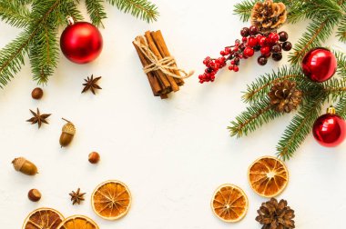 Beyaz Noel arka planı portakal dilimleri, anason yıldızları, tarçın, fındık, ladin dalı ve kırmızı böğürtlenlerle dolu. en üstteki görünüm
