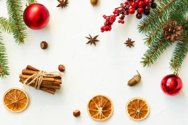 Beyaz Noel arkaplanının üst görüntüsü ladin dalları, jagdalar, kırmızı toplar, portakal salgıları, tarçın ve anason yıldızları. düz yerleşim